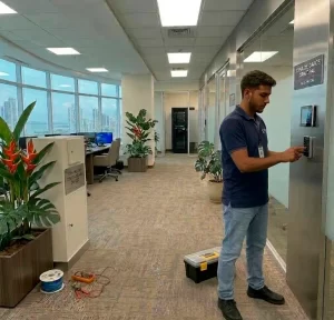 Técnico configurando un teclado numérico y sistema de acceso de control para restringir la entrada a un centro de cómputo con herramientas profesionales.
