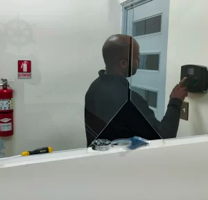 Primer plano de la configuración de un sistema de acceso de control con lector de huella dactilar y teclado numérico instalado en un marco de puerta.